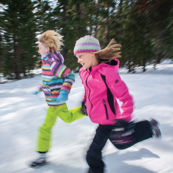 Two girls running in the snow